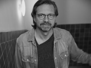 Robert Werner, co-founder of Leapter, in a black and white portrait taken in a tiled hallway.