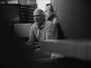 Leapter co-founders Robert Werner and Oliver Welte in conversation, photographed candidly in black and white through a partially obscured frame.